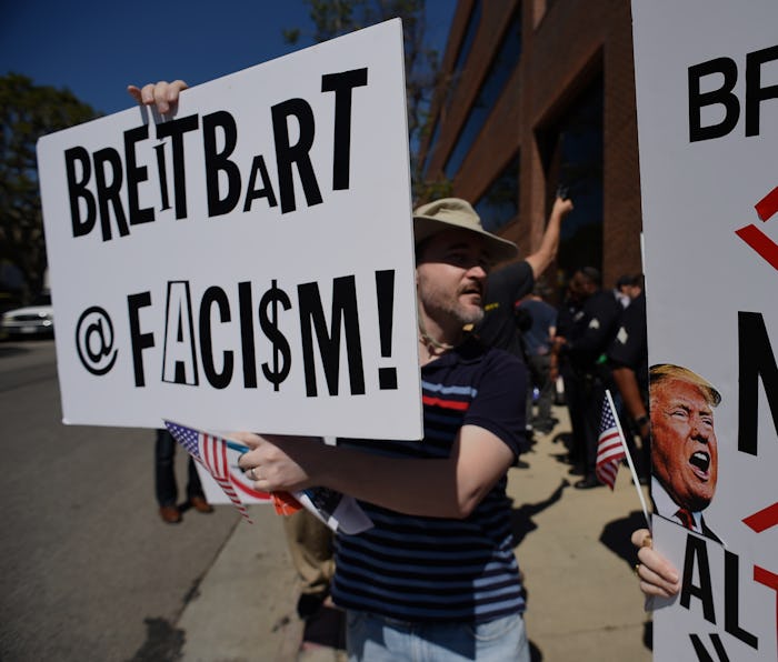 Protestors hold up signs equating Breitbart to fascism and fake news. 