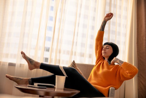 A woman sits on her couch preparing to ask her landlord to reduce her rent.