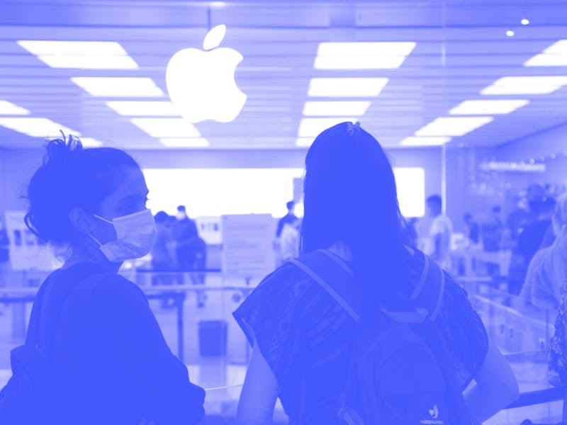 A customer can be seen wearing a mask near an Apple retail store. They are joined by another person ...