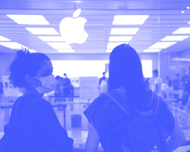 A customer can be seen wearing a mask near an Apple retail store. They are joined by another person ...