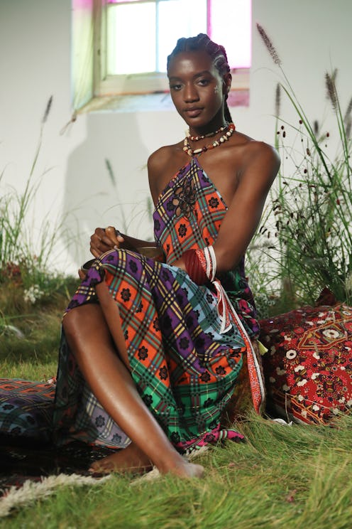 A young black woman sitting in the colorful dress in the plant house