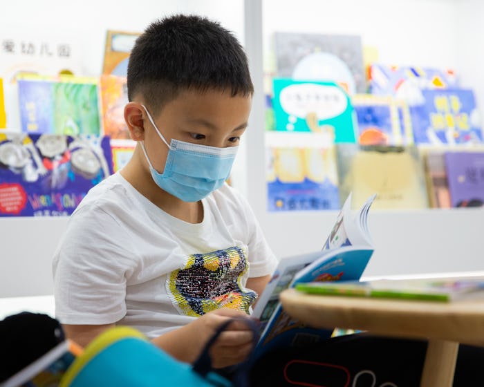 kid read book with face mask