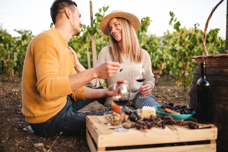 A couple sits outside with their wine and cheese board. 