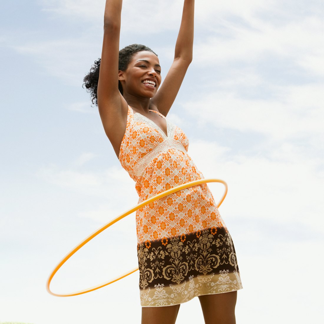 A woman hula hoops. These nostalgic outdoor activities make excellent workouts as an adult.