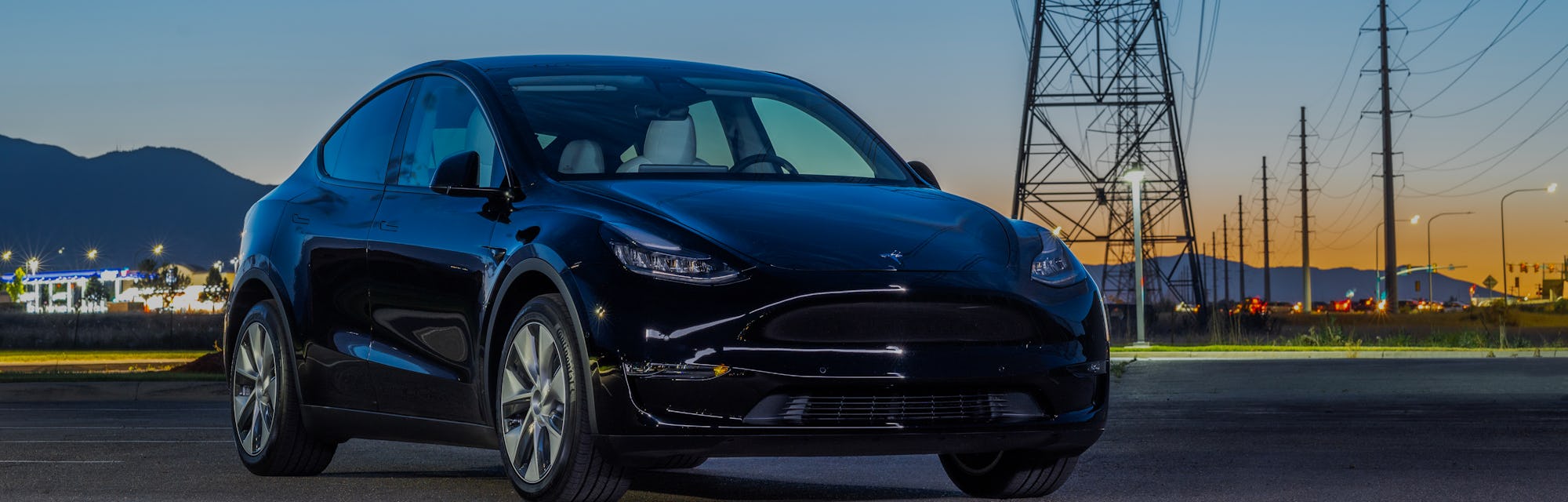 A Tesla car parked in front of power lines.