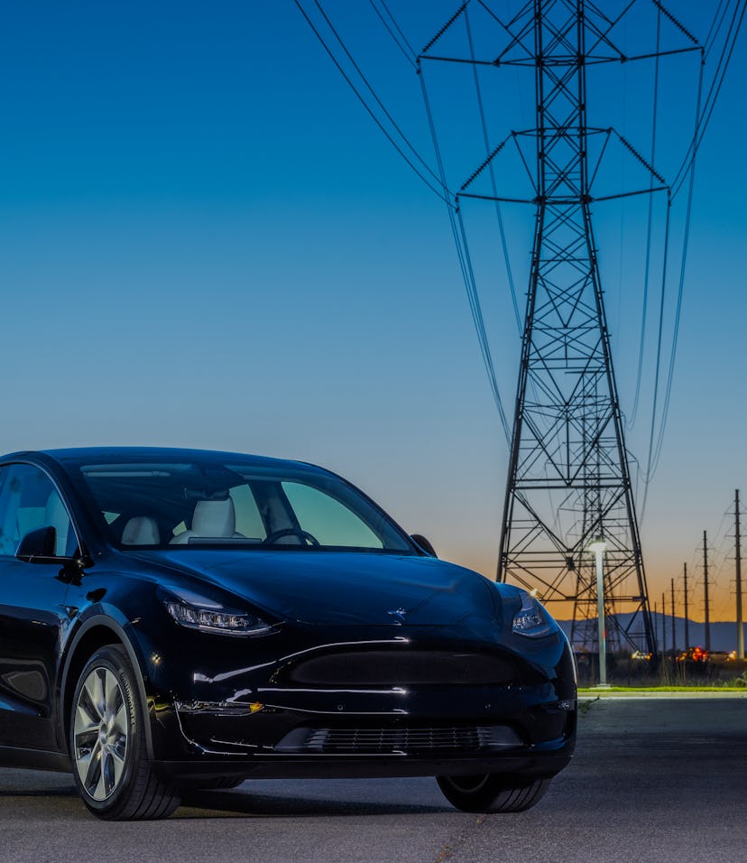 A Tesla car parked in front of power lines.