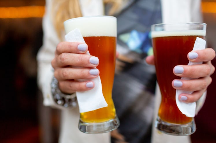 Female hands holding a two glasses of beer.