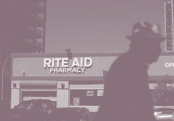 A pedestrian can be seen walking in front of a Rite Aid store. 