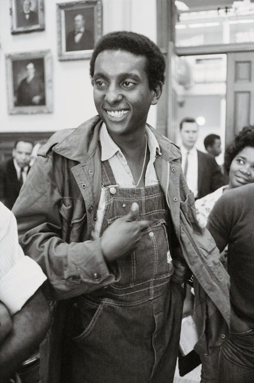 A Black activist smiling while wearing denim overalls