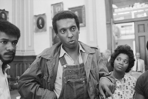 Three Black activists, and the one standing in the middle is sporting denim overalls