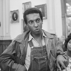 Three Black activists, and the one standing in the middle is sporting denim overalls