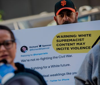 Protestors hold up sign about violent Twitter content.