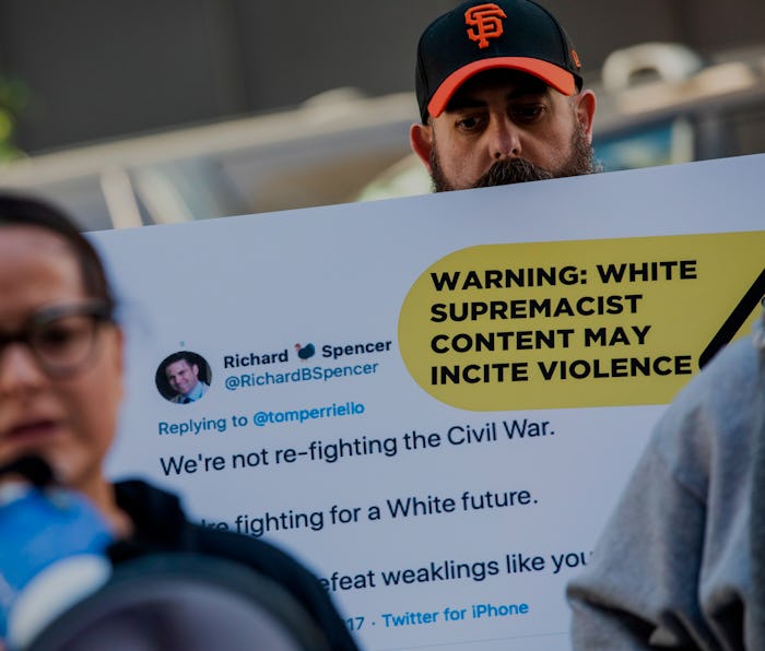 Protestors hold up sign about violent Twitter content.