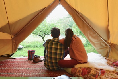 A couple sits in their decorated camping tent. 