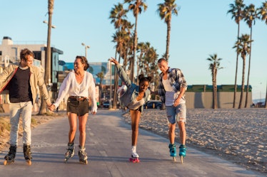 A group of friends wearing roller skates, skate down the beach during the summer. 