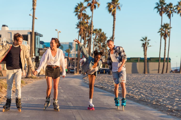 A group of friends wearing roller skates, skate down the beach during the summer.