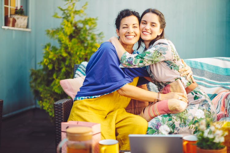 A happy mother and daughter hug each other, while sitting in the backyard.