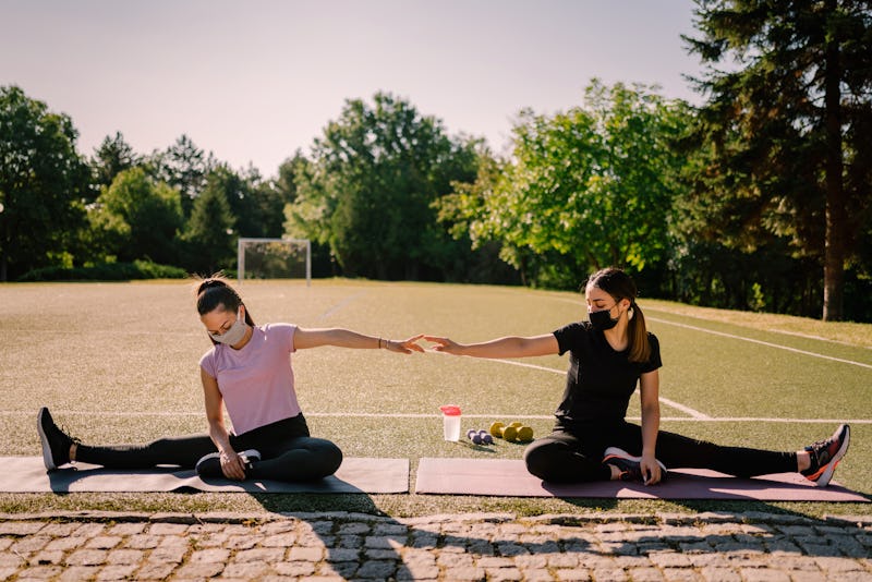 Two women in masks sit at a park. This article debunks myths about how coronavirus spreads with doct...