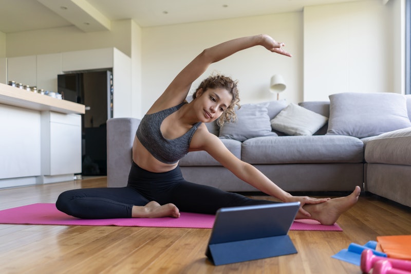 A person does yoga in her living room, using a tablet to guide her. Certain yoga poses can make you ...