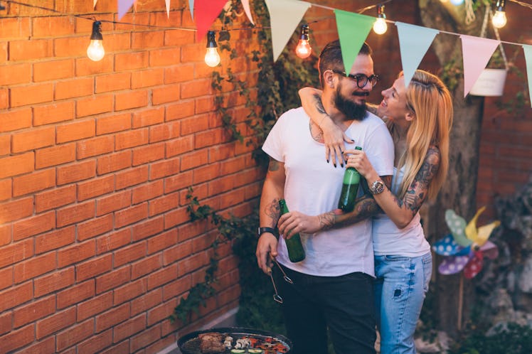 A happy couple barbecues in the backyard together.