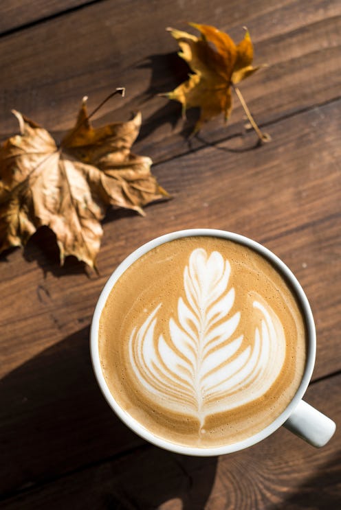 A latte sits next to fall leaves. Pumpkin spices' health benefits will leave you craving a latte.