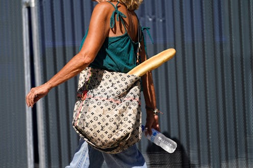 A woman carrying a baguette bread in a stylish shopping bag