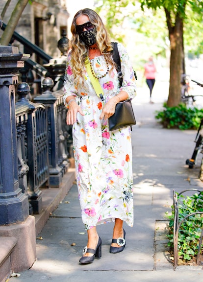 Sarah Jessica Parker in a white floral maxi dress, black sunglasses, facemask, bag and shoes