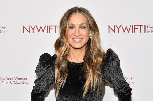 Sarah Jessica Parker smiling in a black velvet dress at a red carpet event