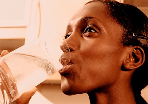 A person smiles as she drinks seltzer. Sparkling water can keep you hydrated just as much as plain w...