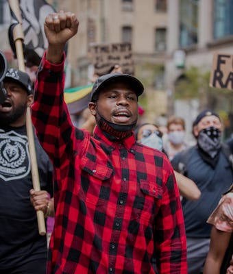 Black Lives Matter activist Derrick Ingram can be seen leading a march. Ingram's right fist is in th...