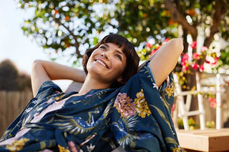 A happy woman lounges out in her garden backyard.