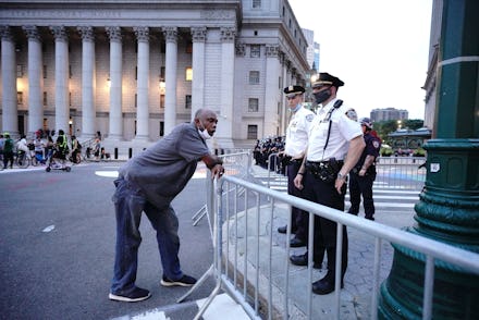 A man leanining on a railing with a police officer on the other side following what he's doing