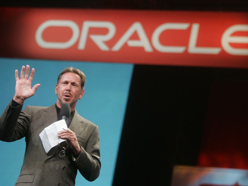 Larry Ellison stands in front of a sign that reads "Oracle."