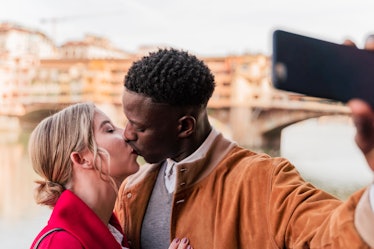 A couple takes an Instagram kissing selfie.