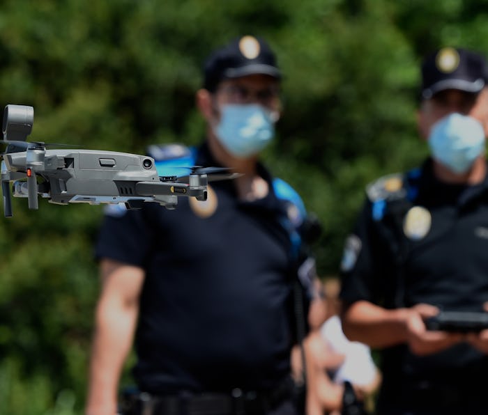 Two masked police officers operate a small drone.