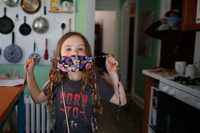 little girl putting on her face mask