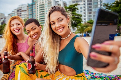 Three young women pose on the beach with their root beers and take a video as an Instagram reel idea...