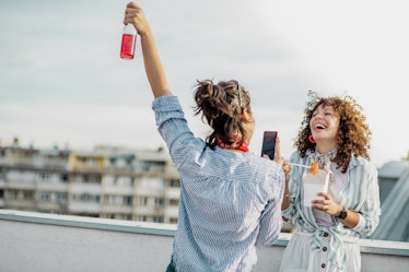 A friend takes a video of her friend eating noodles on their rooftop. 