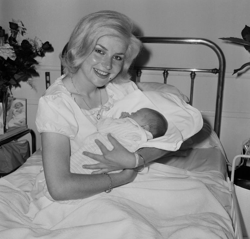 A smiling mom and baby look serene in this vintage maternity ward photo. 