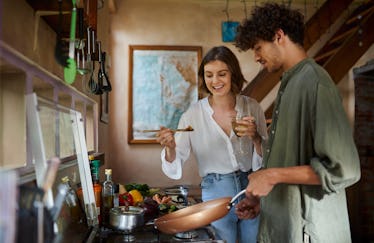 A happy couple cooks together in their kitchen. 