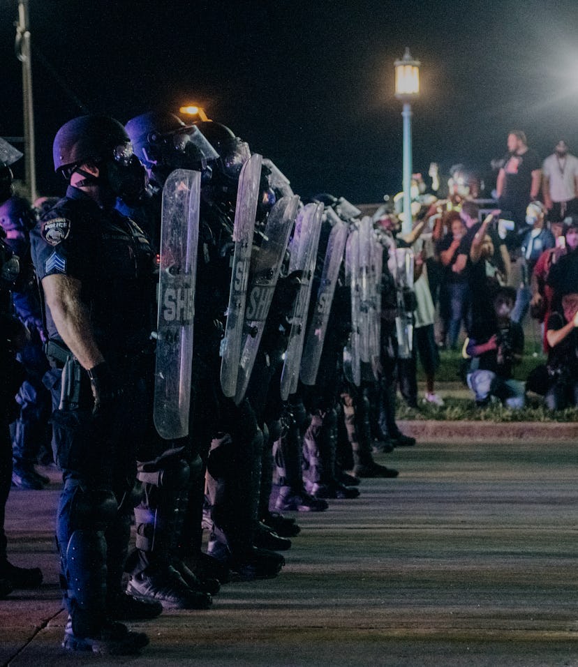 A line of cops in riot gear face protestors in Kenosha.