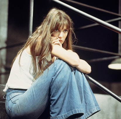 Young woman wears a basic white tank with flared jeans in the 1970s.