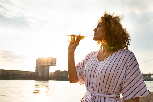 A woman drinks a beer while on the water. This article describes signs your body can't tolerate beer...