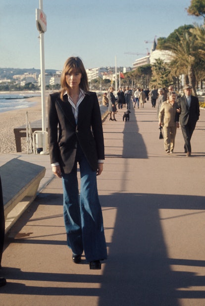 Woman wears a classic black blazer with flared blue jeans on the boardwalk in the 1970s.