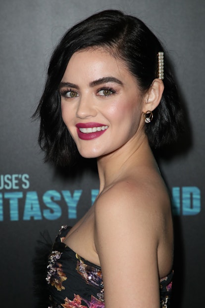Lucy Hale posing on the red carpet with a messy black bob hairstyle, accessorized with a pearly hair...