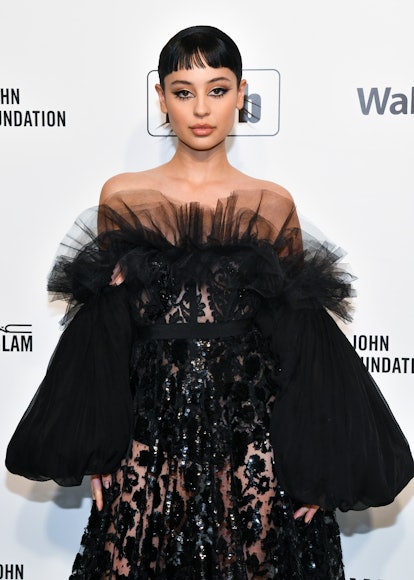 Alexa Demie posing on the red carpet with bold eyeliner under a slick black up do with baby bangs. 
