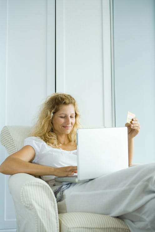 A woman sits with a laptop in a beige armchair. Facebook's classic design is going away. Here's what...