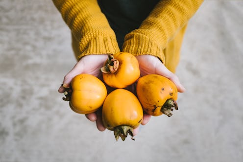 A woman holds persimmons. Vitamin C is marketed as a booster for the immune system, but it doesn't h...