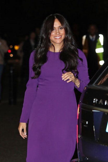 Meghan Markle with a dark brown hairstyle cut in long wavy layers. 