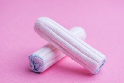 Two clean tampons on a pink background. OB-GYNs explain how the flu can affect your period.